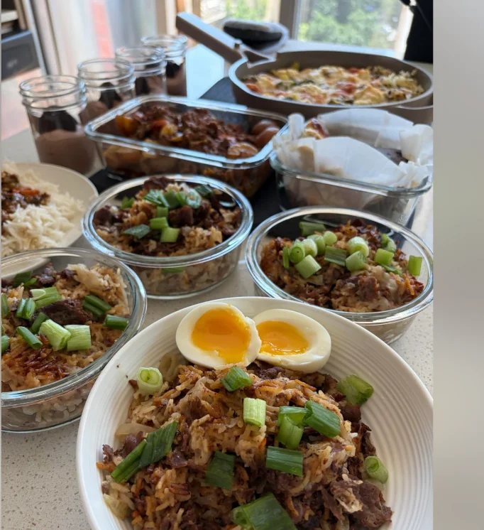A meal-prep spread: glass bowls of beef bulgogi over rice topped with green onions, soft-boiled eggs, and casserole dishes